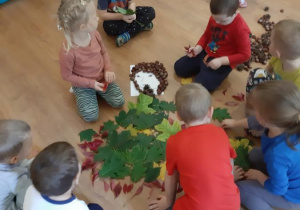 Dzieci wspólnie tworzą obraz Pani Jesieni z materiałów przyrodniczych.